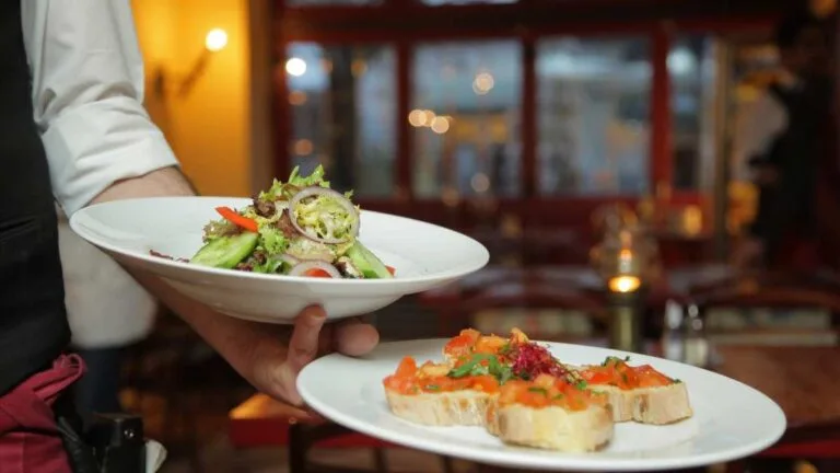 Waiter serving a fresh salad and bruschetta at a restaurant