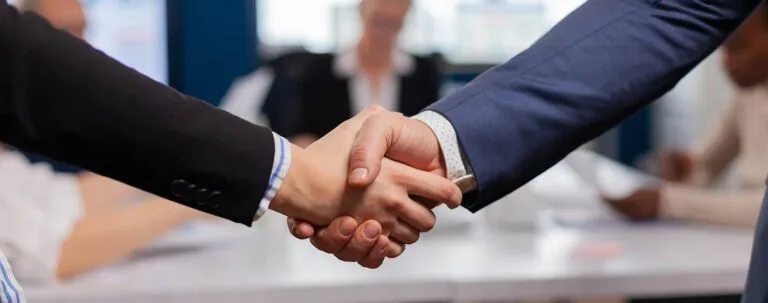 Business partnership handshake in a corporate meeting – hospitality recruitment services